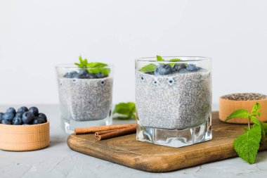 Sağlıklı kahvaltı ve chia tohumlu vanilyalı puding ve böğürtlenli masa arkası, vejetaryen gıda, diyet ve sağlık konsepti. Hindistan cevizi sütü ve yabanmersinli Chia pudingi..