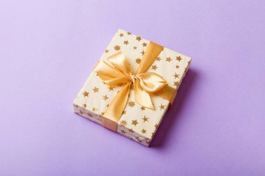 Noel 'i ya da diğer tatil hediyelerini renkli arka planda altın kurdeleli beyaz kağıda sardım. Şimdiki kutu, renkli tabloda hediye süslemesi, kopya alanı ile üst görünüm.