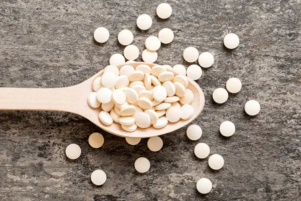 Renkli arka planda bir yığın beyaz hap. Tabletler masaya saçılmış. Kırmızı yumuşak jelatin kapsül yığını. Vitaminler ve beslenme takviyeleri konsepti.