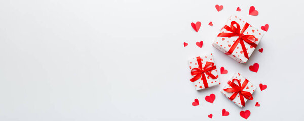 Valentine day composition: red gift box with bow and heart. Christmas present. View from above. Space for text. Holday greeting card.