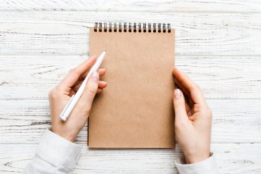 Defterine kalem yazan kadın eli. Ofis masasında çalışan bir kadın. Kalem ve çizim defterini tutan kadın. Model Konsepti.