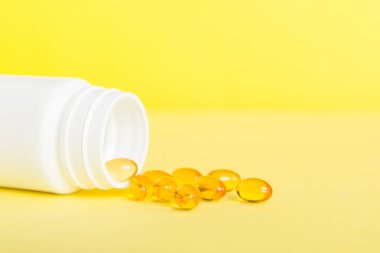 Yumuşak jel hapları ve Omega-3 yağı hap şişesinden sızıyor. Jel kapsülleri beyaz yüzey şişesi. Omega 3, multivitamin, kalsiyum, antibiyotik. Sağlığa. Dokunulmazlık.