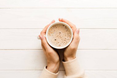 Renkli arka planda bir fincan kahve tutan minimalist stil bir kadın. Düz yerde, kapuçino bardağının üstünde. Metin için boş yer, kopyalama alanı. Kahve bağımlılığı. Üst manzara, düz uzanma.