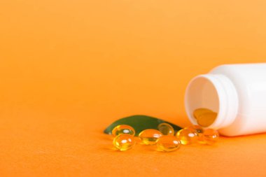 Yumuşak jel hapları ve Omega-3 yağı hap şişesinden sızıyor. Jel kapsülleri beyaz yüzey şişesi. Omega 3, multivitamin, kalsiyum, antibiyotik. Sağlığa. Dokunulmazlık.