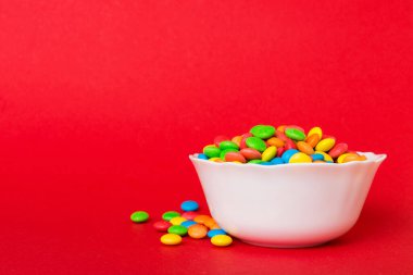 Renkli arka planda bir kasede çok renkli şekerler. Doğum günü ve tatil konsepti. Kopyalama alanı olan üst görünüm.