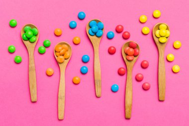 Renkli arka planda kaşık üzerinde renkli tatlı şekerler. Fotokopi alanı ile şekerleme dekoru üst görünümü.