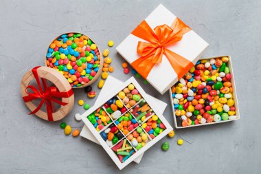 Renkli bir arka planda saten bir kurdeleyle karton kutuda farklı şekerler. Tatil kavramı.