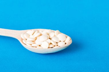 Renkli arka planda bir yığın beyaz hap. Tabletler masaya saçılmış. Kırmızı yumuşak jelatin kapsül yığını. Vitaminler ve beslenme takviyeleri konsepti.
