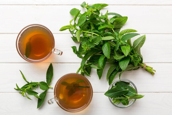 Чашка мятного чая на фоне стола. Зеленый чай со свежим мятным видом сверху с копировальным пространством.