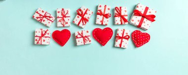 Hediye kutularının ve renkli arka planda kırmızı tekstil kalplerinin üst görüntüsü. Kopya alanı ile Sevgililer Günü konsepti.