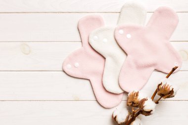 Üzerinde pamuk çiçekleri olan renkli, yeniden kullanılabilir adet pedleri. sıfır atık kadın dönemi konsepti kopya alanı ile üst görünüm.