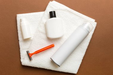 Tıraş Adam seti. Traş makinesi, havlu, losyon ve renkli arka planda tıraş köpüğü. Erkekler banyo aksesuarları üst görünüm.