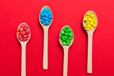 Renkli arka planda kaşık üzerinde renkli tatlı şekerler. Fotokopi alanı ile şekerleme dekoru üst görünümü.