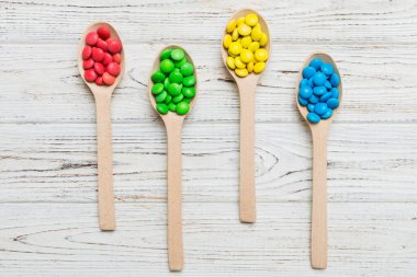 Renkli arka planda kaşık üzerinde renkli tatlı şekerler. Fotokopi alanı ile şekerleme dekoru üst görünümü.