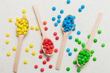 Renkli arka planda kaşık üzerinde renkli tatlı şekerler. Fotokopi alanı ile şekerleme dekoru üst görünümü.