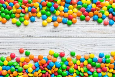 Renkli arka planda karışık renkli şeker koleksiyonu. Düz yerde, üst tarafta. Renkli çikolata kaplı şeker çerçevesi.