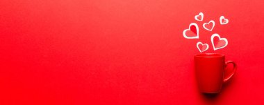 Renkli arka planda kırmızı bardak, kırmızı küçük kalpler, kopya alanı ile üst görünüm.