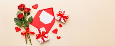 Zarflı sevgililer günü kompozisyonu, gül çiçeği ve kırmızı kalp masada. Üst manzara, düz yatış. Tatil kavramı.