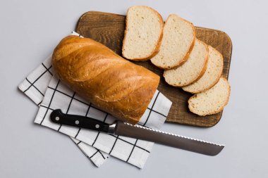 Tahtada bıçakla kesilmiş taze pişmiş ekmek. Üst manzara Dilimlenmiş ekmek ve bıçak.