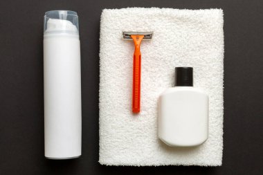 Tıraş Adam seti. Traş makinesi, havlu, losyon ve renkli arka planda tıraş köpüğü. Erkekler banyo aksesuarları üst görünüm.