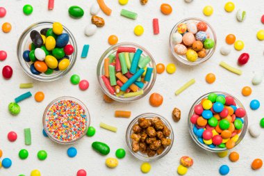 farklı renkte yuvarlak şekerler ve kavanozlar. Fotokopi alanı olan büyük çeşitlilikteki şeker ve şekerlerin üst görünümü.