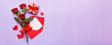 Zarflı sevgililer günü kompozisyonu, gül çiçeği ve kırmızı kalp masada. Üst manzara, düz yatış. Tatil kavramı.
