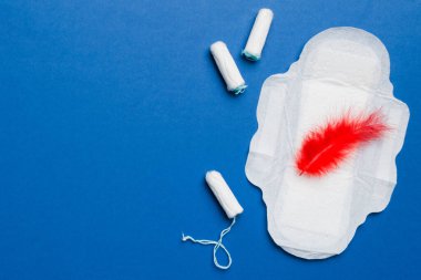Kadın pedleri ve tamponları. Pembe ve menekşe arka planda izole edilmiş bir arka planda hijyenik pedlerin yanında uzanıyor. Kadın hijyeni ve adet dönemi konsepti.