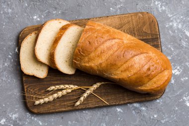 Tahtayı keserken beyaz ahşap zemin üzerinde taze pişmiş ekmek dilimleri. Üst görünüm Dilimlenmiş ekmek.