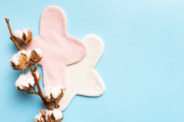 Üzerinde pamuk çiçekleri olan renkli, yeniden kullanılabilir adet pedleri. sıfır atık kadın dönemi konsepti kopya alanı ile üst görünüm.