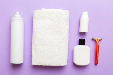 Tıraş Adam seti. Traş makinesi, havlu, losyon ve renkli arka planda tıraş köpüğü. Erkekler banyo aksesuarları üst görünüm.