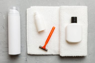 Tıraş Adam seti. Traş makinesi, havlu, losyon ve renkli arka planda tıraş köpüğü. Erkekler banyo aksesuarları üst görünüm.