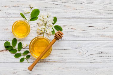 Akasya çiçekli ve yapraklı bal kavanozu. Taze bal üst görünüm düz yatıyordu.