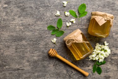 Akasya çiçekli ve yapraklı bal kavanozu. Taze bal üst görünüm düz yatıyordu.