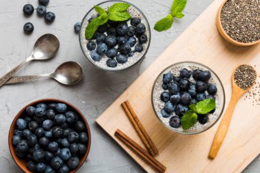 Sağlıklı kahvaltı ve chia tohumlu vanilyalı puding ve böğürtlenli masa arkası, vejetaryen gıda, diyet ve sağlık konsepti. Hindistan cevizi sütü ve yabanmersinli Chia pudingi..