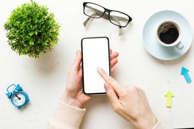 Mesajınız veya bilgi içeriğiniz için boş bir kopya ekranı olan akıllı telefonları tutan kadın ellerinin üst görünümü. üst görünümde telefon beyaz ekranı kullanan kadın eli.