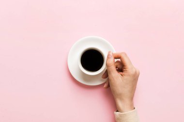 Renkli arka planda bir fincan kahve tutan minimalist stil bir kadın. Düz yerde, kapuçino bardağının üstünde. Metin için boş yer, kopyalama alanı. Kahve bağımlılığı. Üst manzara, düz uzanma.
