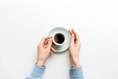 Renkli arka planda bir fincan kahve tutan minimalist stil bir kadın. Düz yatıyordu, üstten espresso fincanı. Metin için boş yer, kopyalama alanı. Kahve bağımlılığı. Üst manzara, düz uzanma.