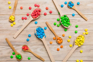 Renkli arka planda kaşık üzerinde renkli tatlı şekerler. Fotokopi alanı ile şekerleme dekoru üst görünümü.