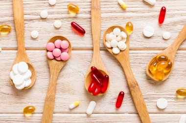 Renkli bir arka planda kaşıkta vitamin kapsülleri. Haplar sağlıklı bir yemek olarak sunuldu. Kırmızı yumuşak jel vitamin takviye kapsülleri kaşık üzerinde.