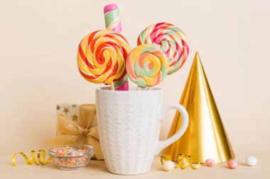 Masanın üzerinde açık arkaplanda renkli şekerler. Büyük kıvrımlı lolipoplar. Şekerci dükkanından leziz şekerlerle dolu yaratıcı bir kavanoz konsepti.