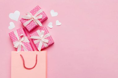 Gift boxes pop out from paper bag top view on colored background. bag packing handmade boxes fall out Concept of holidays, shopping, sale, discounts. Top view, flat lay.