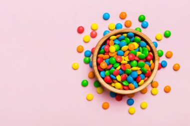 Renkli arka planda bir kasede çok renkli şekerler. Doğum günü ve tatil konsepti. Kopyalama alanı olan üst görünüm.