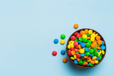 Renkli arka planda bir kasede çok renkli şekerler. Doğum günü ve tatil konsepti. Kopyalama alanı olan üst görünüm.