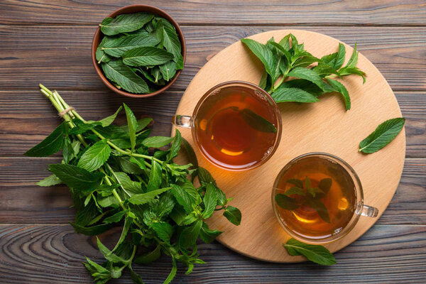 Чашка мятного чая на фоне стола. Зеленый чай со свежим мятным видом сверху с копировальным пространством.