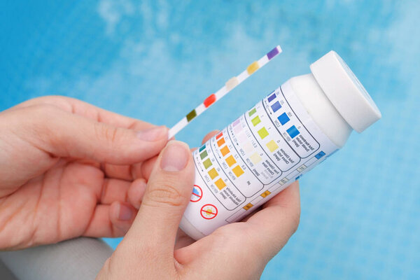 Анализ PH и хлора воды в бассейне летом. Проверка качества воды с тестовой полосой, сравнение результатов.