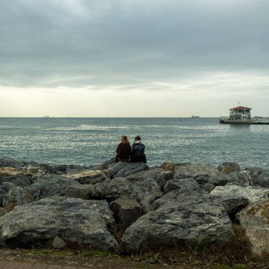 beautiful couple on the beach with a sea and stones, beautiful view of the city of istanbul with tourists in the sea, person watching the sea