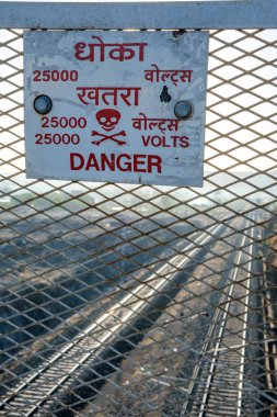 25 bin voltluk tehlike işareti Pune India yakınlarındaki bir köprüden geçiyor. Bu tür işaretler Hindistan 'daki elektrikli demiryolu bölümlerinin üzerindeki köprülere rutin olarak konur..