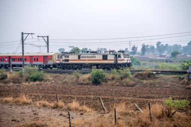 Pune, Hindistan - 07 Mayıs 2023: Pune Hindistan yakınlarında WAP7 elektrikli bir lokomotif tarafından taşınan yolcu treni.