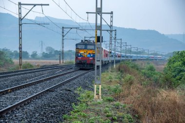 Pune, Hindistan - 07 Mayıs 2023: Pune Hindistan yakınlarında bir WCAM3 elektrikli lokomotifi tarafından taşınan yolcu treni.