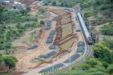 Pune, Hindistan - 15 Ağustos 2023: Pune Hindistan yakınlarında bir WCAM3 elektrikli lokomotifi tarafından taşınan yolcu treni.